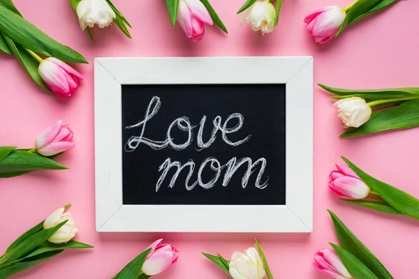 Top view of tulips around chalkboard with love mom lettering on pink background — Stock Photo