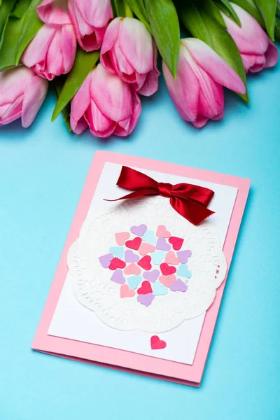 Grußkarte in der Nähe von Strauß von Tulpen auf blauem Hintergrund — Stockfoto