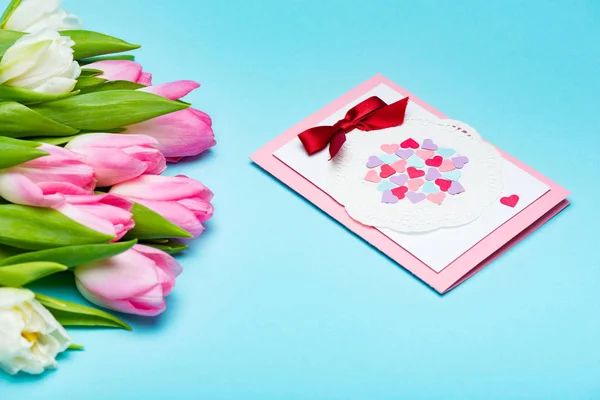 Bouquet di tulipani vicino biglietto di auguri su superficie blu — Foto stock