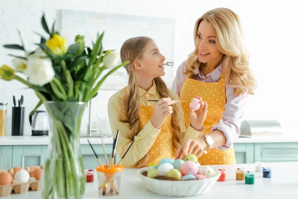 Selective focus of happy child holding easter egg and looking at mother — Stock Photo