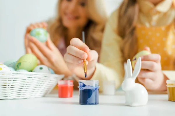 Selective focus of decorative bunny near kid holding paintbrush near jar with paint — Stock Photo