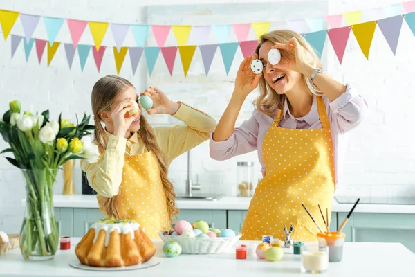 Feliz hija y madre cubriendo los ojos con huevos pintados de Pascua — Stock Photo
