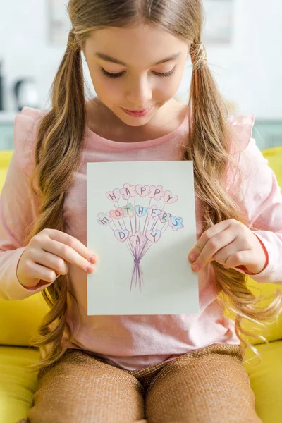 Adorable enfant regardant carte de vœux avec joyeux lettrage de la fête des mères — Photo de stock