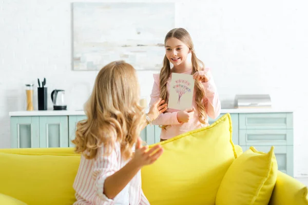Selektiver Fokus glücklicher Kinder mit Glückwunschkarte mit glücklichem Muttertagsaufdruck in der Nähe der Mutter — Stockfoto