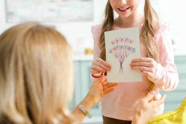 Обрезанный вид счастливой дочери держа поздравительную открытку с счастливыми матерями день письма рядом с матерью — стоковое фото