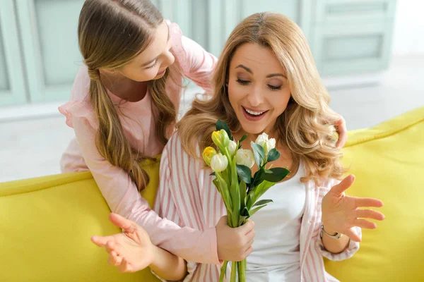 Cute kid giving bouquet of tulips to surprised mother — Stock Photo