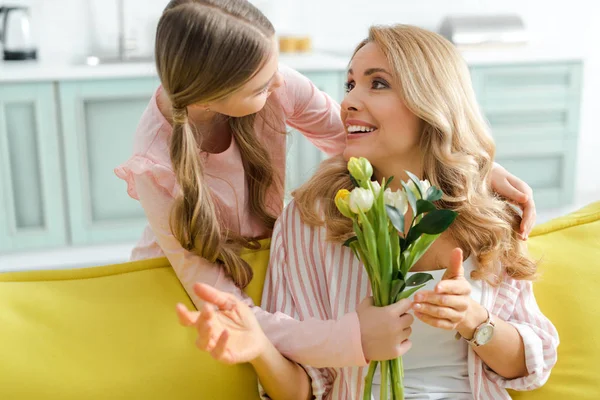 Cute kid giving bouquet of tulips to smiling mother — Stock Photo