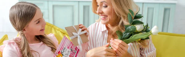 Панорамный снимок веселого ребенка с подарками и поздравительной открыткой с надписью 