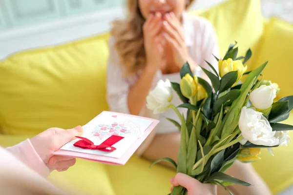 Fuoco selettivo di figlia che tiene il biglietto di auguri con cuori e fiori vicino a madre — Foto stock