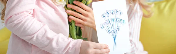 Panoramaaufnahme eines Kindes mit Glückwunschkarte mit Muttertagsaufdruck in der Nähe der Mutter — Stockfoto