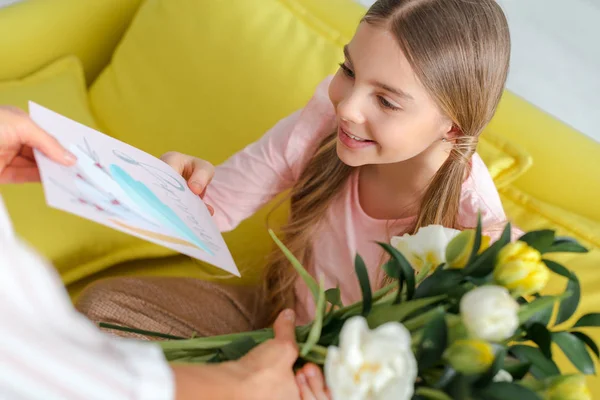 Messa a fuoco selettiva di bambino felice che prende tulipani e biglietto di auguri con 8 lettere di marcia vicino alla madre — Foto stock