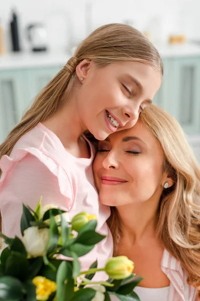 Избирательный фокус счастливой матери и дочери, улыбающихся рядом с тюльпанами — стоковое фото