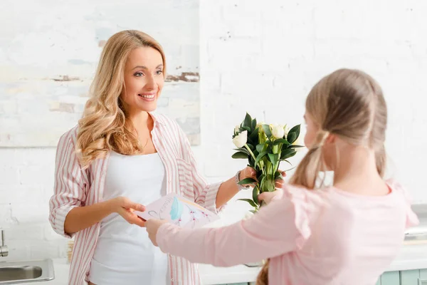 Enfoque selectivo del niño sosteniendo tulipanes y tarjeta de felicitación con 8 letras de marzo cerca de la madre - foto de stock