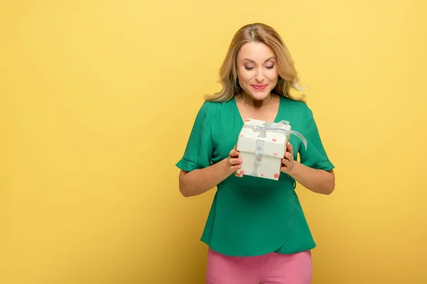 Donna allegra in possesso di scatola regalo isolato su giallo — Foto stock