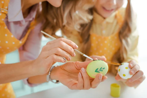 Vue recadrée de mère et fille peignant des œufs de poulet sur Pâques — Photo de stock