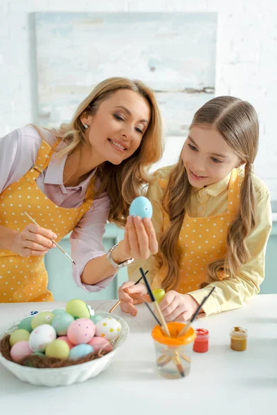 Happy woman and adorable kid looking at painted chicken egg on easter — Stock Photo