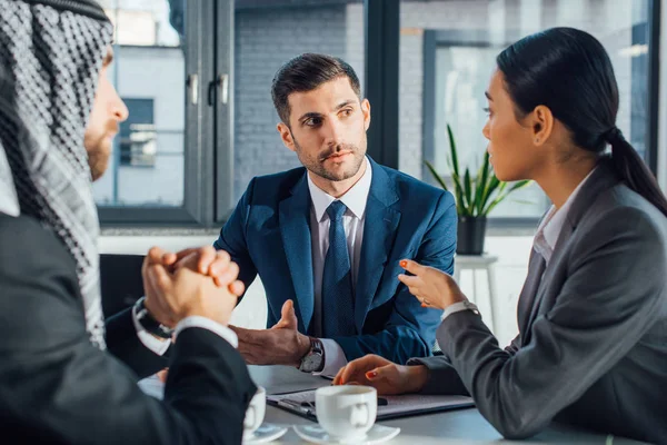 Socios comerciales multiculturales que conversan sobre la reunión con el traductor en la oficina - foto de stock