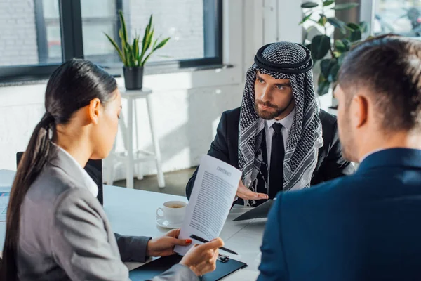 Socios comerciales multiculturales discutiendo contrato en reunión con traductor profesional en la oficina - foto de stock