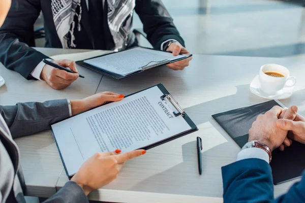 Cropped view of business partners holding contract on meeting in office — Stock Photo