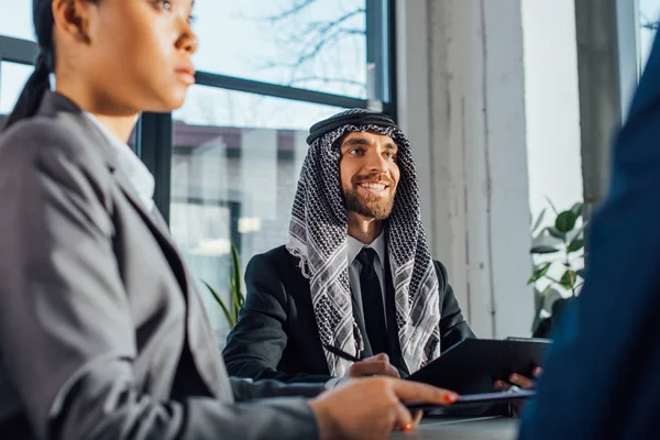 Des partenaires commerciaux multiculturels souriants discutant de leur rencontre avec un traducteur en poste — Photo de stock