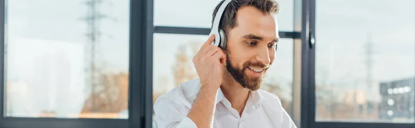 Tiro panorâmico de tradutor sorridente profissional trabalhando online com fones de ouvido e laptop — Fotografia de Stock