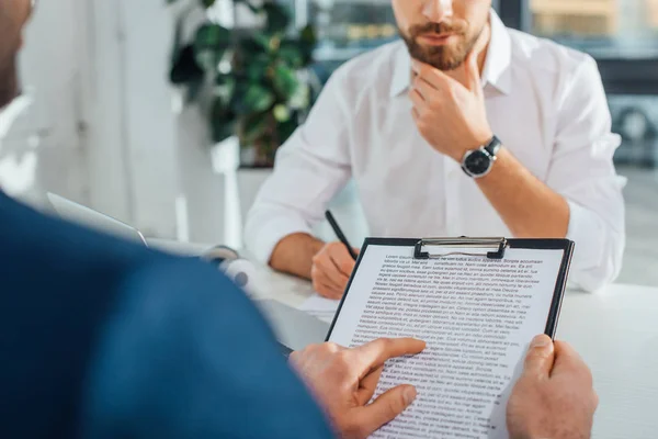 Vista recortada del traductor que trabaja con el hombre de negocios y documentos en la oficina moderna - foto de stock