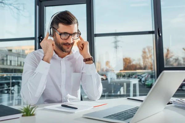 Traducteur professionnel masculin dans les lunettes de travail en ligne avec écouteurs et ordinateur portable — Photo de stock