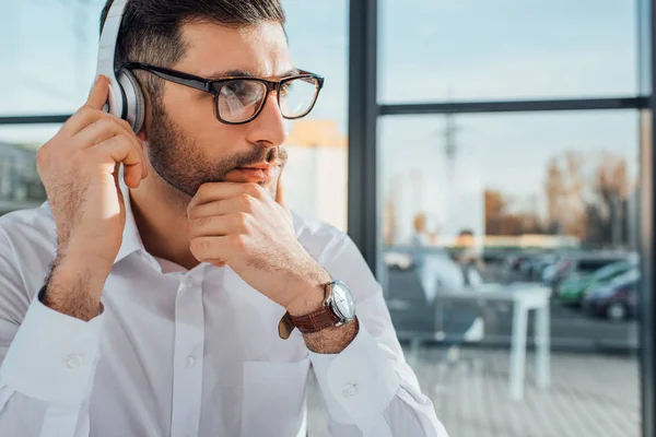 Traductor masculino en gafas graduadas que trabajan en línea con auriculares - foto de stock