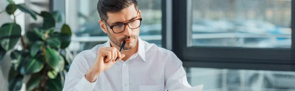 Panoramic shot of thoughtful translator working with documents in office — Stock Photo