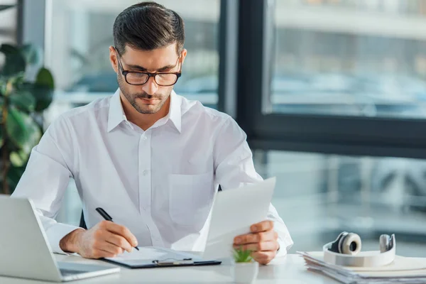 Concentrated translator writing and working with documents in office — Stock Photo