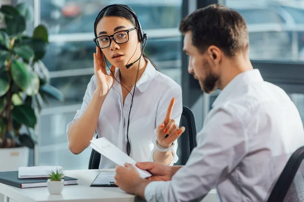 Professionista asiatico traduttore lavoro online con cuffia pur avendo incontro con uomo d'affari — Foto stock