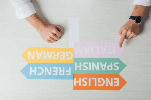 Top view of translator pointing at arrows with languages — Stock Photo