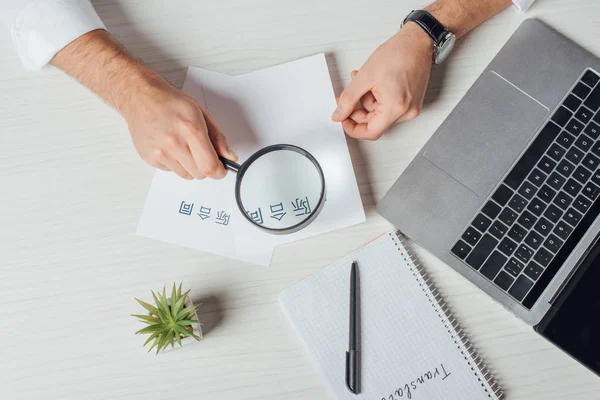 Cropped view of translator working with hieroglyphics, laptop and magnifying glass — Stock Photo