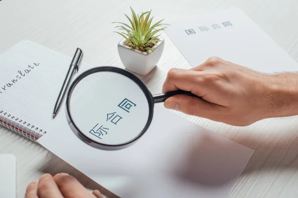 Cropped view of translator working with hieroglyphics and magnifying glass — Stock Photo