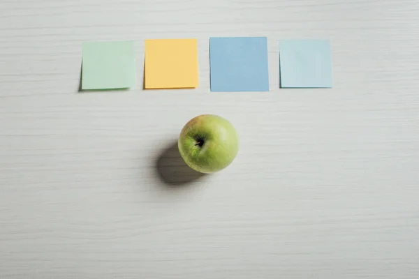 Vue du dessus des autocollants pomme verte et note vide sur la table — Photo de stock