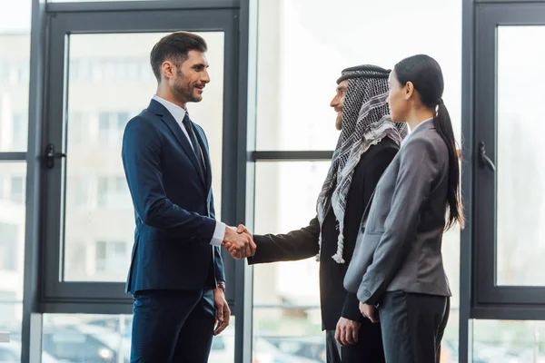 Профессиональные мультикультурные деловые партнеры пожимают руку на встрече с переводчиком в офисе — стоковое фото