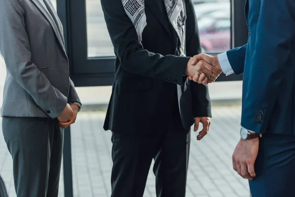 Обрезанный взгляд профессиональных бизнесменов пожимающих руки и имеющих дело в современном офисе — стоковое фото