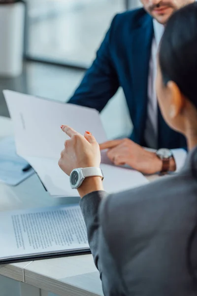 Cropped view of businessman and businesswoman discussing contract in modern office — Stock Photo