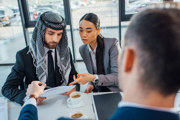 Multicultural business partners discussing contract on meeting with translator in office — Stock Photo