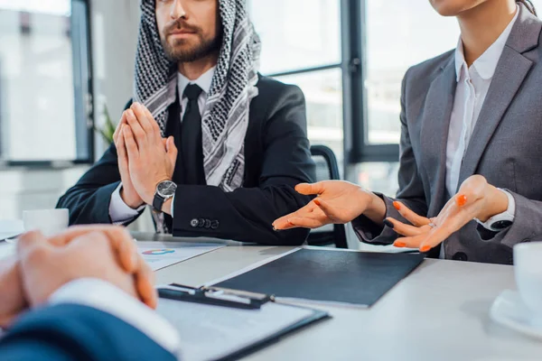 Vista cortada de parceiros de negócios multiculturais conversando em reunião com tradutor no escritório — Fotografia de Stock