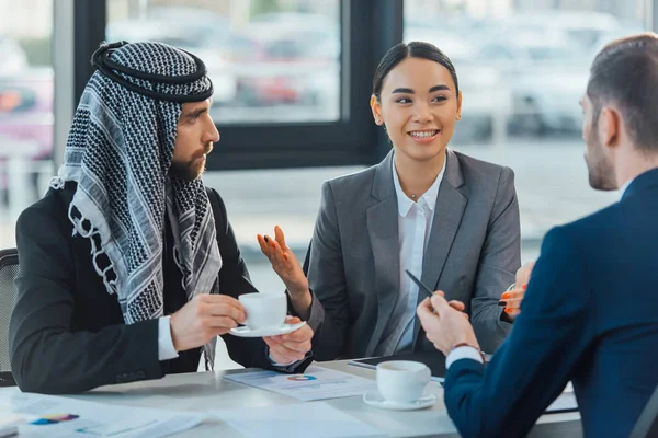 Heureux partenaires d'affaires multiethniques sur la rencontre avec le traducteur au bureau — Photo de stock