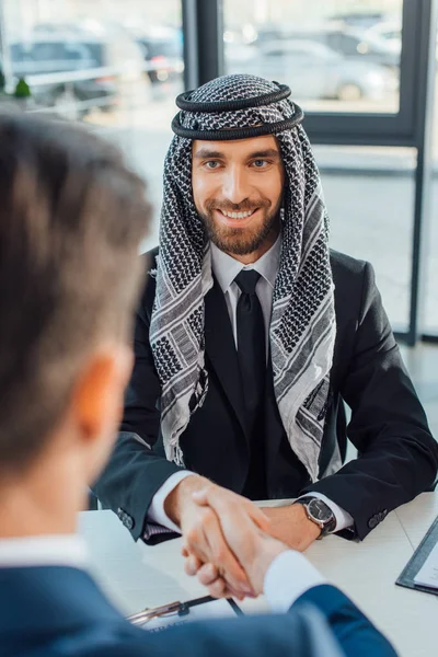 Sonriente hombre de negocios multiétnico estrechando la mano con su pareja en la reunión — Stock Photo