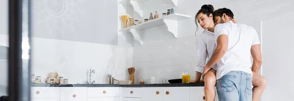 Homme baisers dans cou attrayant copine en chemise sur cuisine plan de travail, panoramique shot — Photo de stock