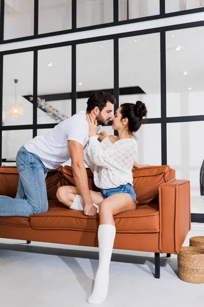 Smiling woman kissing boyfriend on couch in living room — Stock Photo