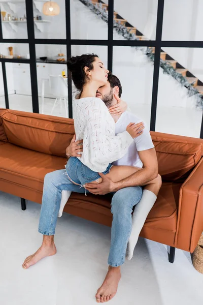Мужчина целует в шею чувственную девушку на диване в гостиной — стоковое фото