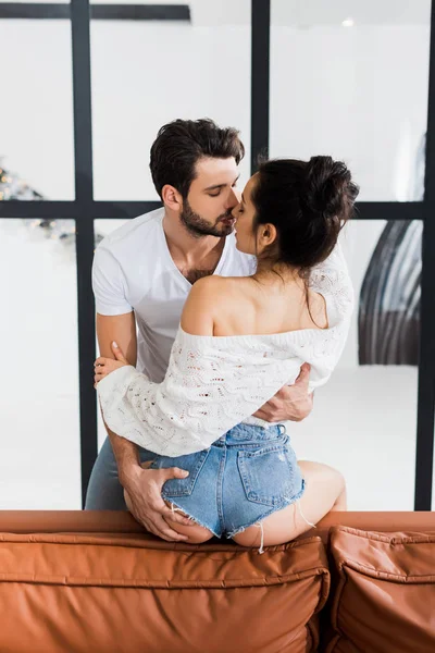 Handsome man kissing and touching by buttocks sensual girlfriend on couch — Stock Photo