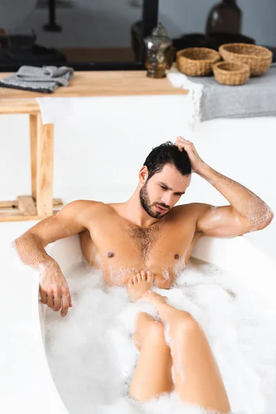 Muscular man looking away while taking bath with girlfriend at home — Stock Photo