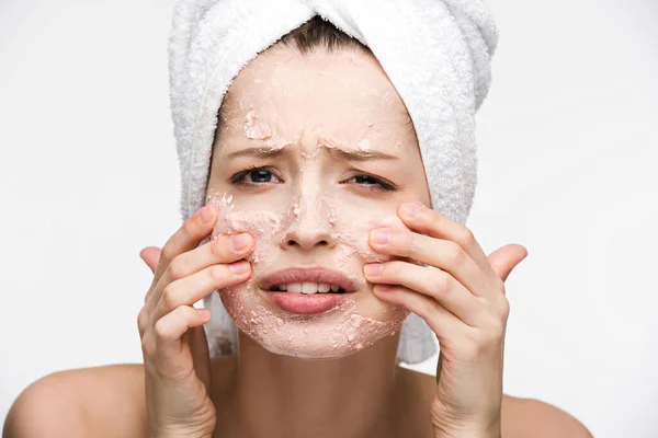 Displeased girl with facial peeling mask touching face isolated on white — Stock Photo