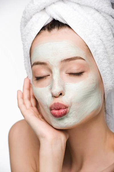 Attractive girl with facial nourishing mask and towel on head making duck face with closed eyes isolated on white — Stock Photo
