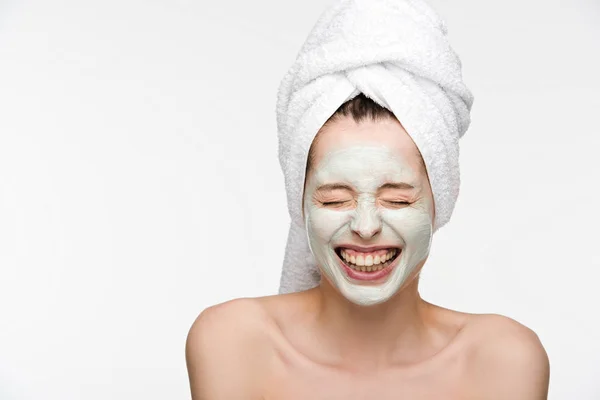 Excited girl with facial nourishing mask and towel on head laughing with closed eyes isolated on white — Stock Photo